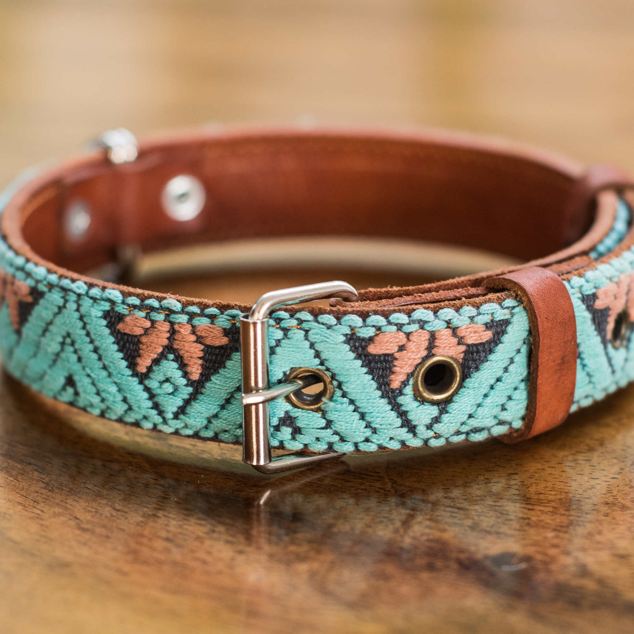 Full view of a teal leather dog collar laid out on a wooden table, emphasizing texture and color.