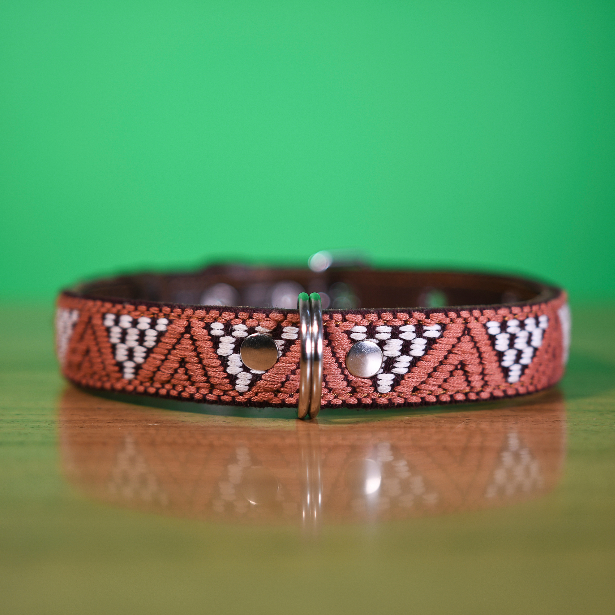 Detailed embroidery on a Brown Rust dog collar over a wooden table, highlighting artistic detail.